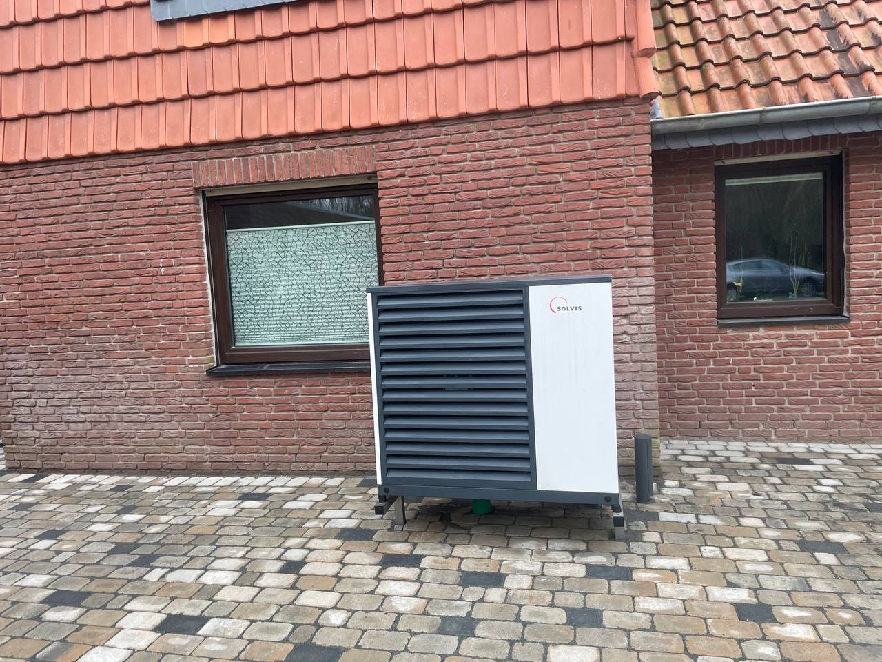 Wärmepumpe Außeneinheit vor modernem Wohnhaus